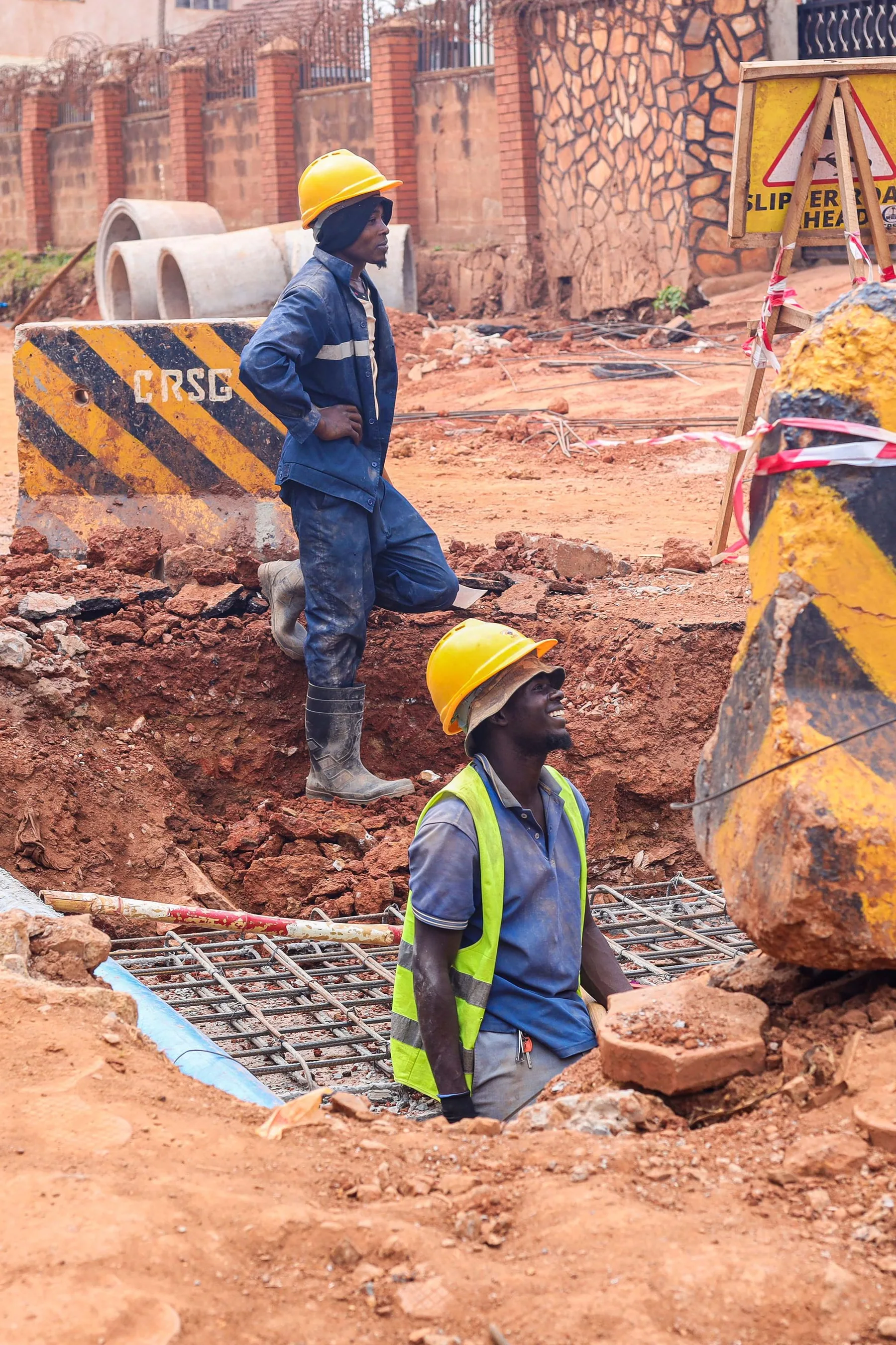 Ouvriers et engins sur un chantier de fondation en terre rouge