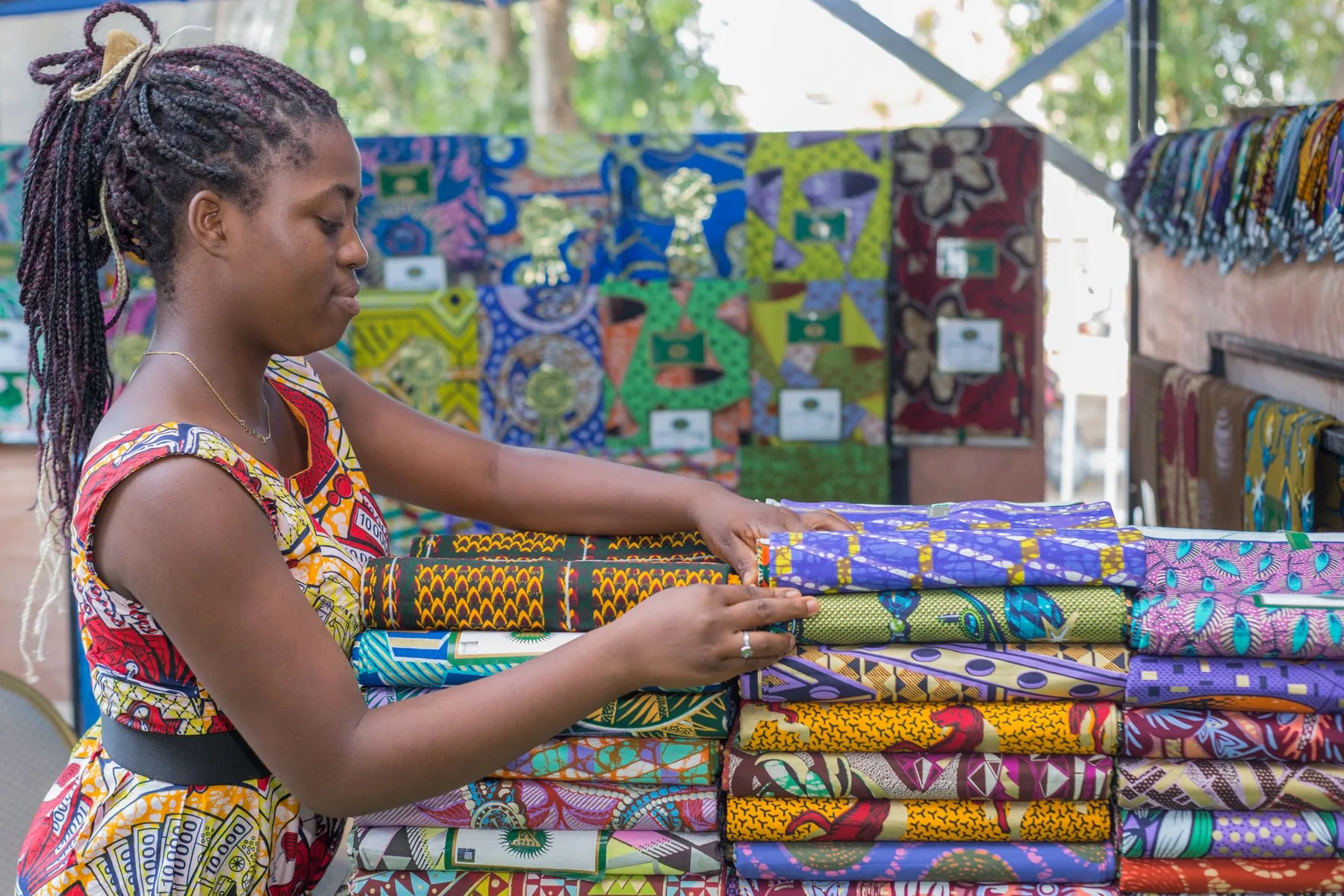 Vendeuse de tissus africains arrangeant des pièces colorées sur son étal