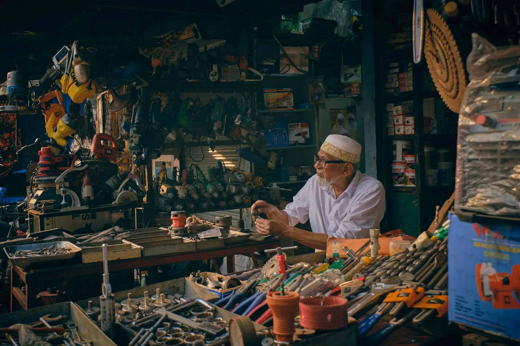 Commerçant dans une quincaillerie, entouré d’outils et d’articles ménagers