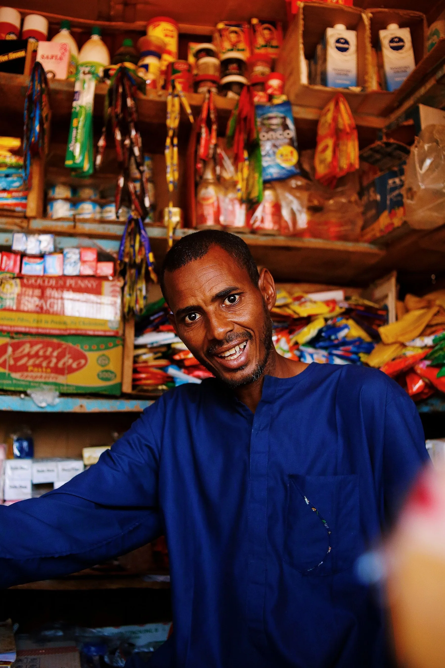 Commerçant en chemise bleue derrière le comptoir de sa boutique